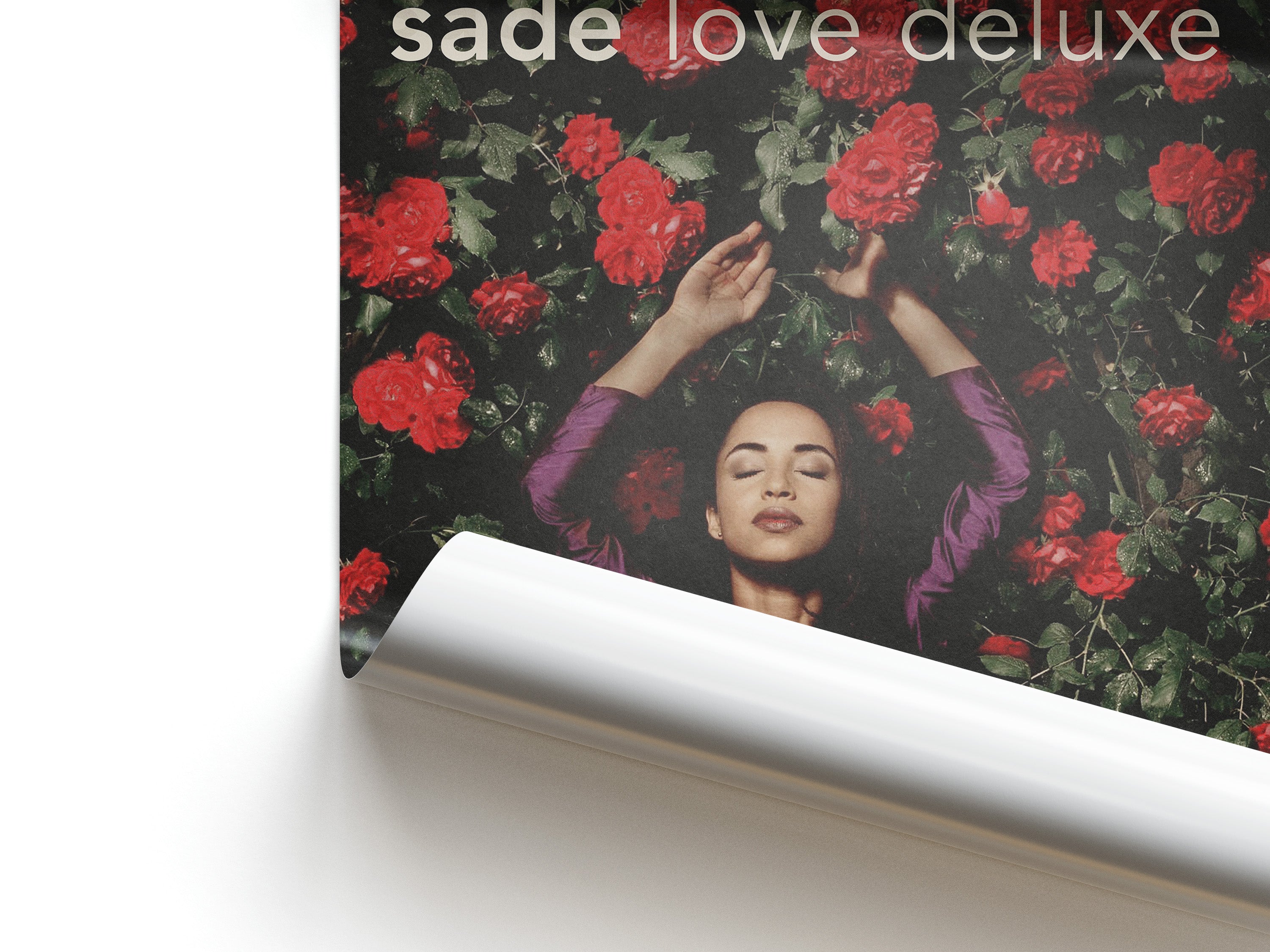 Album cover with a woman surrounded by red flowers and 'sade love deluxe' text.