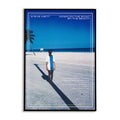 Poster of a person standing on a road with a beach and palm tree in the background. 